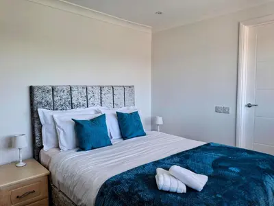 a bedroom with a large bed with blue pillows at Modern townhouse with easy access to London in Ingatestone
