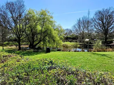 a park with a pond and trees and grass at Modern townhouse with easy access to London in Ingatestone
