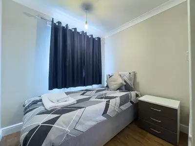 a bedroom with a bed with a black curtain at Urban Ease Basildon in Basildon