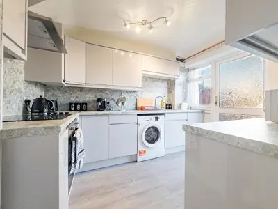 a kitchen with white cabinets and a washer and dryer at Urban Ease Basildon in Basildon