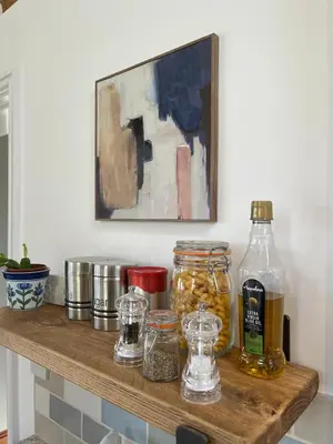 a wooden shelf with jars of food and a painting at Elm Barn in Diss