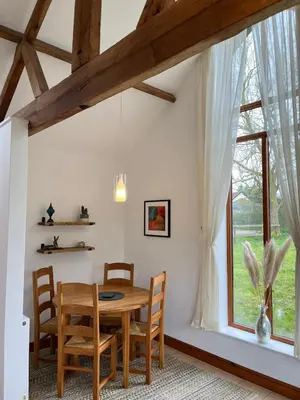 a dining room with a wooden table and a window at Elm Barn in Diss