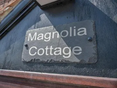 a sign on the side of a building at Magnolia Cottage your cosy Getaway Pass the Keys in Chelmsford