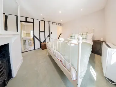 a bedroom with a white bed and a fireplace at Magnolia Cottage your cosy Getaway Pass the Keys in Chelmsford