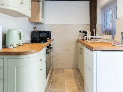 a kitchen with white cabinets and wooden counter tops at Magnolia Cottage your cosy Getaway Pass the Keys in Chelmsford