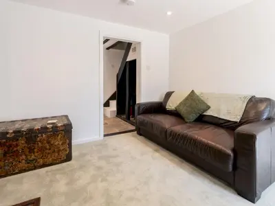 a living room with a brown leather couch and an open door at Magnolia Cottage your cosy Getaway Pass the Keys in Chelmsford
