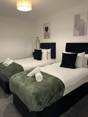 two beds in a hotel room with towels on them at 5 Bed Home near Anglesey Abbey in Swaffham Bulbeck