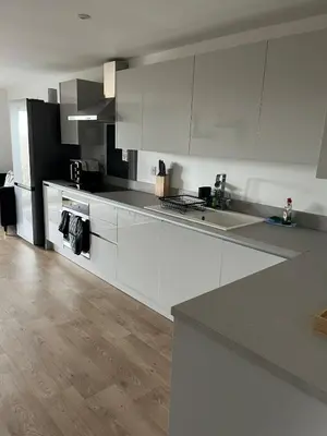 a kitchen with white cabinets and a wooden floor at 5 Bed Home near Anglesey Abbey in Swaffham Bulbeck
