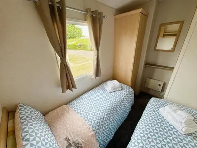 a small bedroom with two beds and a window at Santos Caravan Beautiful Holiday Home in Clacton-on-Sea