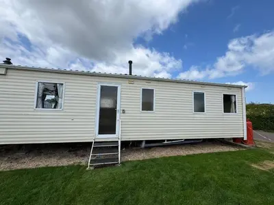 a white house with a ladder in a yard at Santos Caravan Beautiful Holiday Home in Clacton-on-Sea