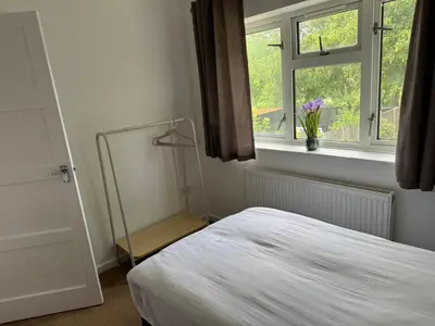 a bedroom with a bed and a window and a mirror at Holly Copse in Stevenage