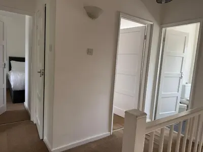 a hallway with white walls and a mirror and a staircase at Holly Copse in Stevenage