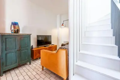 a living room with a staircase and a television at Edinburgh House 4 in Aldeburgh