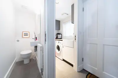 a white bathroom with a toilet and a washing machine at Edinburgh House 4 in Aldeburgh