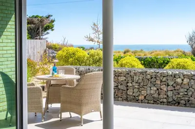 a patio with a table and chairs and a stone wall at Heath House 4 in Thorpeness