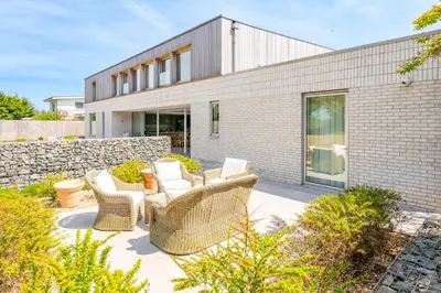 a patio with wicker furniture in front of a brick building at Heath House in Thorpeness