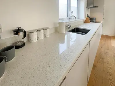 a kitchen with white counters and a sink at Modern stylish house in Charming Fen Ditton Village in CBG