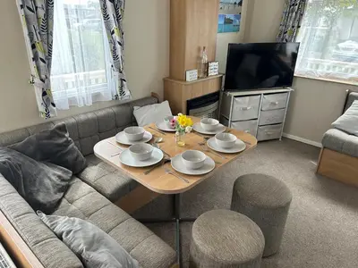 a living room with a table and a couch at Perfect days away - 3 bedroom 1 shower with decking & bedding in Colchester