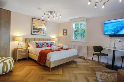a bedroom with a bed and a table and a tv at Very best location - Luxury Studio by river and historic city centre in Cambridge