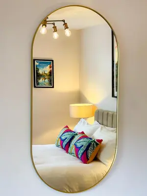 a mirror in a bedroom with a bed and pillows at Very best location - Luxury Studio by river and historic city centre in Cambridge