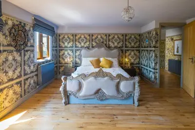 a bedroom with a bed with blue and gold wallpaper at Huge 8 Bed Manor House with Hot Tub, Cinema Room, Games Room in Hailsham