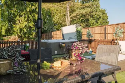 a patio table with an umbrella and a grill at Huge 8 Bed Manor House with Hot Tub, Cinema Room, Games Room in Hailsham