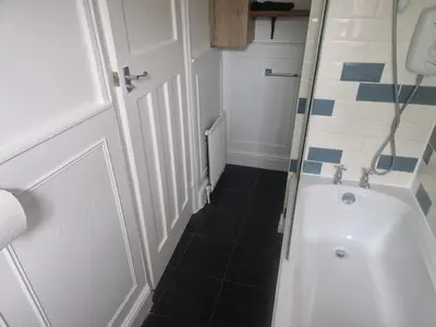 a small bathroom with a shower and a sink at 1930s conversion two apartment in Harold Wood