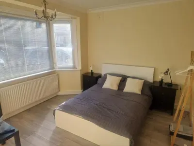 a bedroom with a bed and two windows and a ladder at 1930s conversion two apartment in Harold Wood
