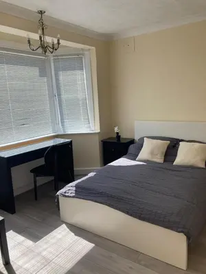 a bedroom with a bed and a desk and a window at 1930s conversion two apartment in Harold Wood