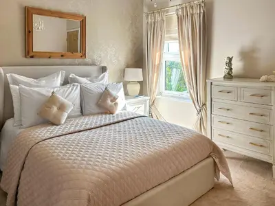 a bedroom with a bed and a dresser and a mirror at Lavender Cottage in Frinton-on-Sea