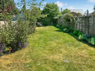 a yard with grass and a fence and some plants at Lavender Cottage in Frinton-on-Sea