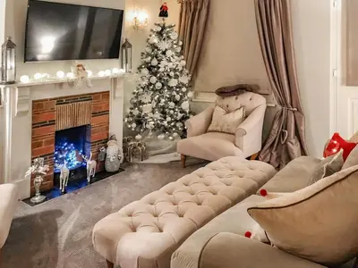 a living room with a christmas tree and a fireplace at Lavender Cottage in Frinton-on-Sea
