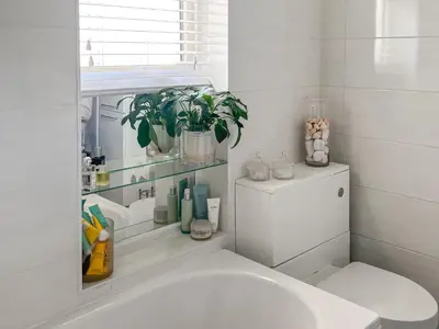 a bathroom with a white sink and a plant at Lavender Cottage in Frinton-on-Sea