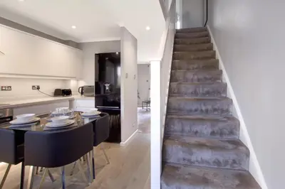 a staircase leading to a dining room and kitchen with a table and chairs at Spotless Two-Bedroom Home with Garden and Parking in Stevenage