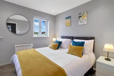 a bedroom with a large bed with yellow and blue pillows at Spotless Two-Bedroom Home with Garden and Parking in Stevenage
