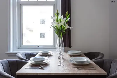a dining room table with plates and a vase of flowers at 1 Bed Apartments, 2 Mins to Beach, Sleeps 4 in Southend-on-Sea