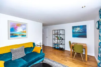 a living room with a blue couch and a table at First Class Flat in Brandon