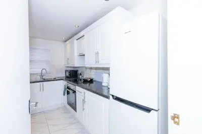 a kitchen with white cabinets and black counter tops at First Class Flat in Brandon