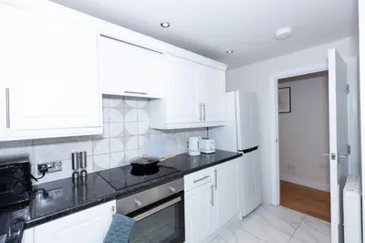 a kitchen with white cabinets and a black counter top at First Class Flat in Brandon