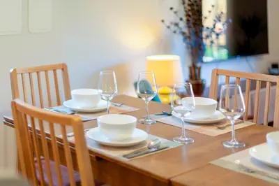 a wooden table with plates and wine glasses on it at Stylish luxury on edge of Cambridge Free Parking Pass the Keys in Cottenham