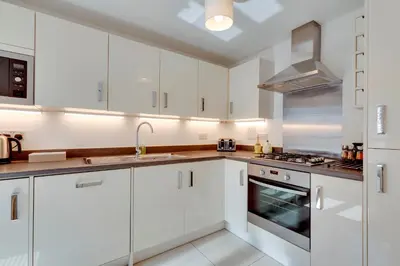 a white kitchen with white cabinets and a sink at Stylish luxury on edge of Cambridge Free Parking Pass the Keys in Cottenham