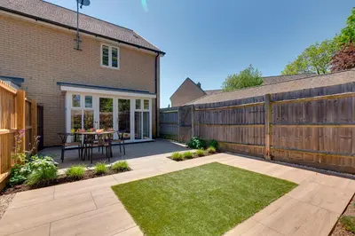 a backyard with a wooden fence and a table at Stylish luxury on edge of Cambridge Free Parking Pass the Keys in Cottenham
