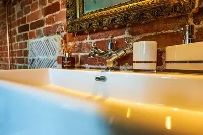 a bathroom sink with two candles and a mirror at Cosy & charming medieval 'Bumble Cottage' in Kersey
