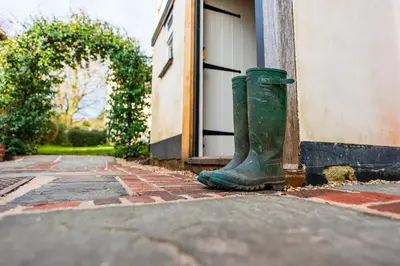 a green boot sitting on the side of a building at Cosy & charming medieval 'Bumble Cottage' in Kersey