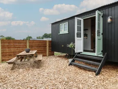 a black tiny house with a bench and a table at The Heron in Cambridge