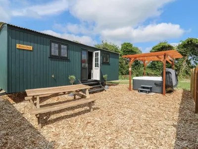 a green tiny house with a bench and a gazebo at Barn Owl in Cambridge