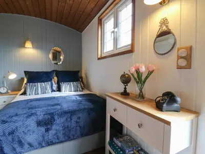 a bedroom with a bed with blue sheets and a window at Barn Owl in Cambridge