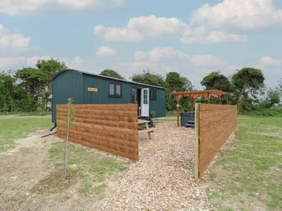 a green tiny house with a wooden fence at Barn Owl in Cambridge