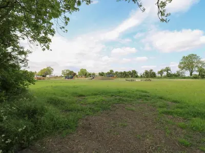 a large green field with trees in the distance at Barn Owl in Cambridge
