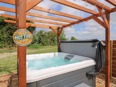a hot tub under a pergola with a sign at Barn Owl in Cambridge